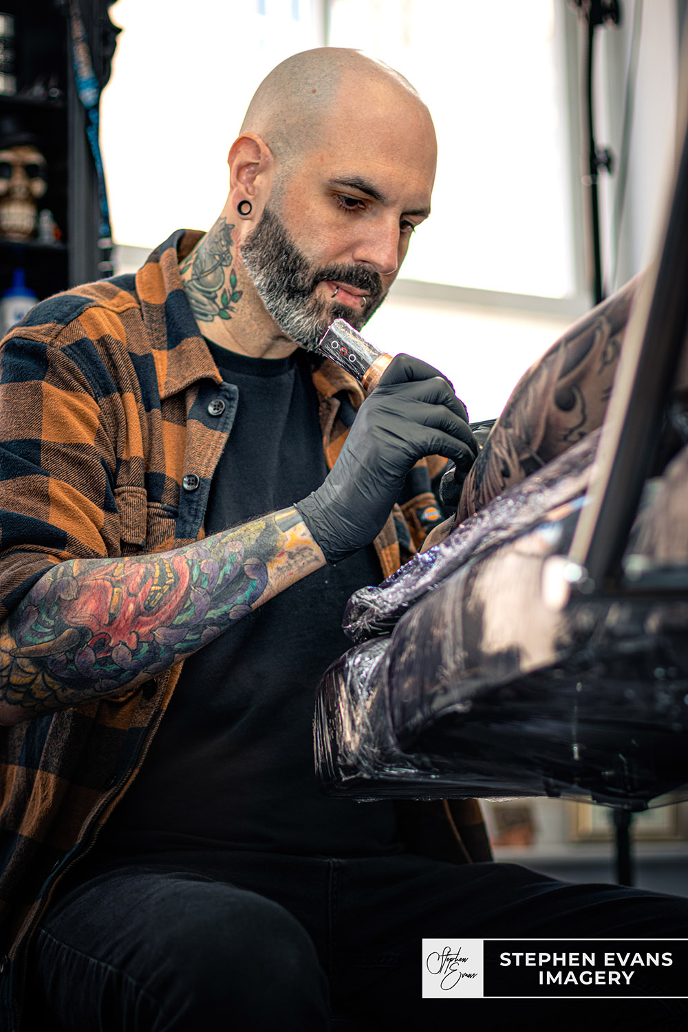 Tattoo artist Mike Harper working on leg tattoo design