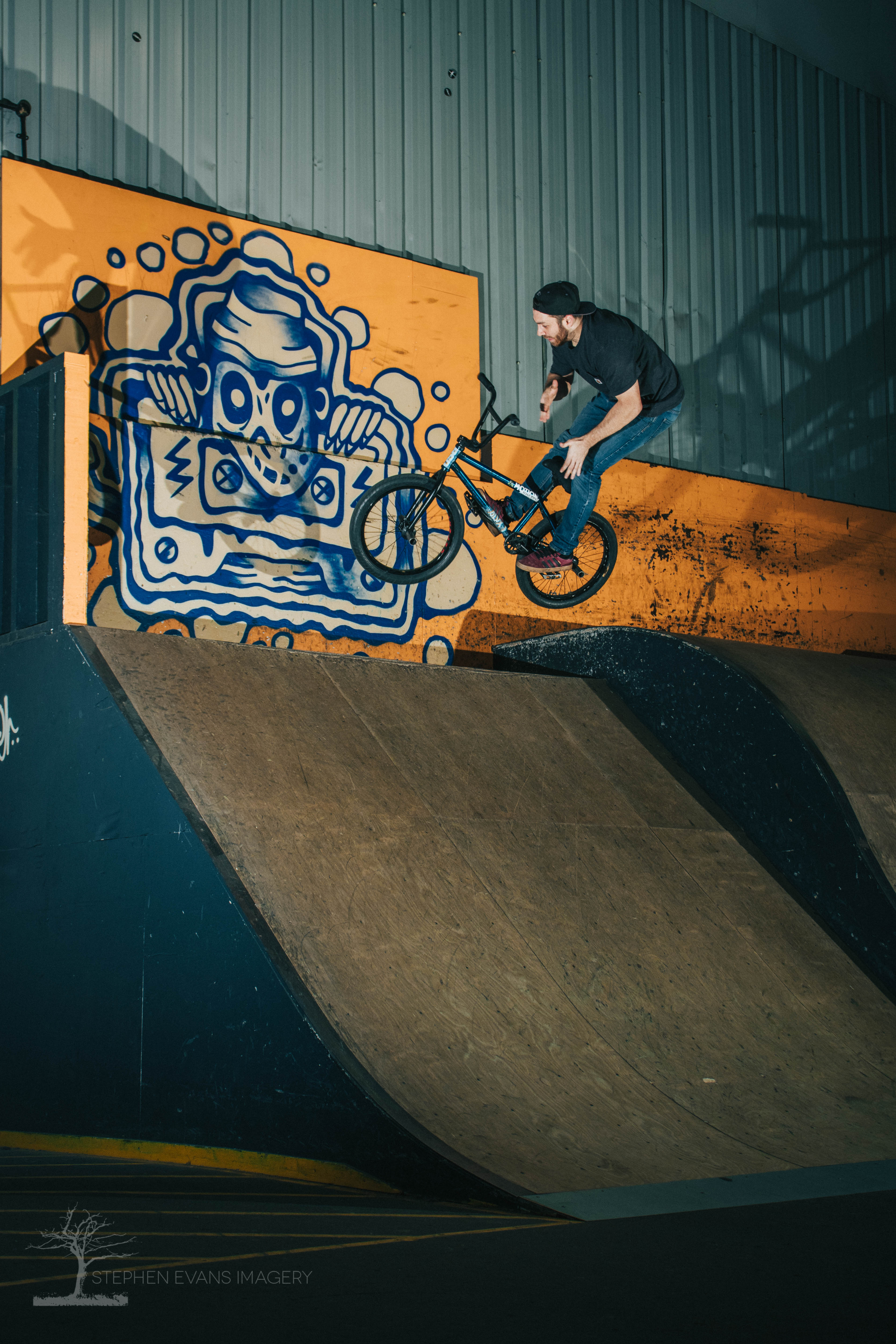 BMX rider Dan performing 180 barspin trick on flatbank at KASET Skatepark